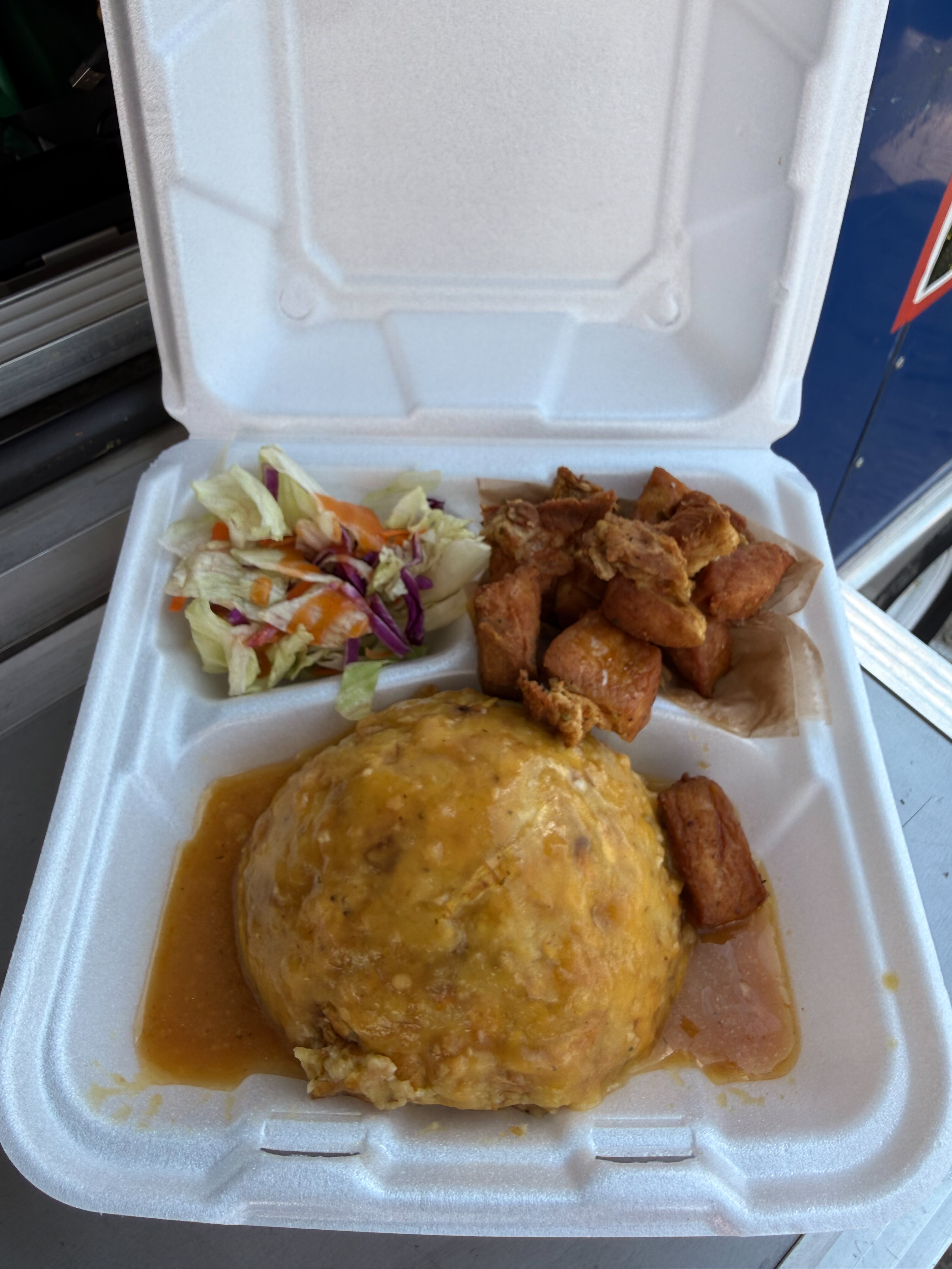 Una caja para llevar de Puerto Rico Flavor: mofongo con salsa de ajo, masitas de cerdo fritas y una ensalada pequeña